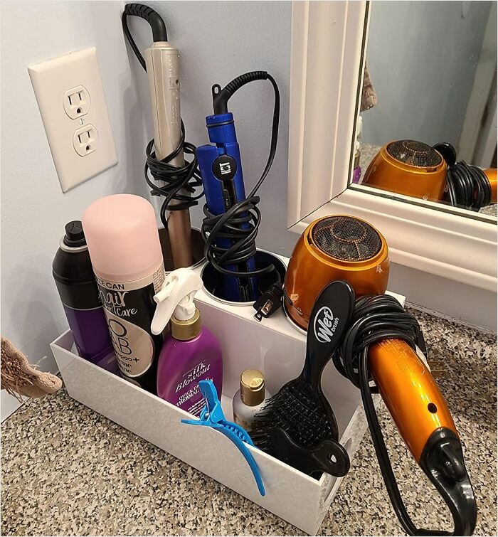 Organized bathroom counter with hair tools and products neatly arranged in a holder.