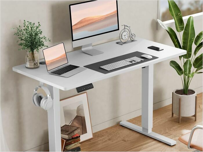 Adjustable standing desk with computer setup, plants, and decor, showcasing excellent reviews on Amazon furniture.