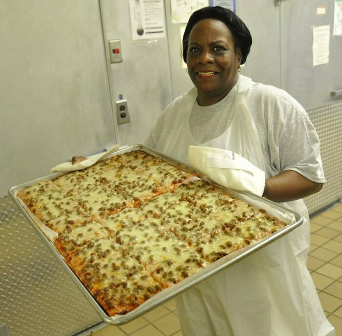 Person holding a large tray of pizza, showcasing unhinged foods planned to be eaten.