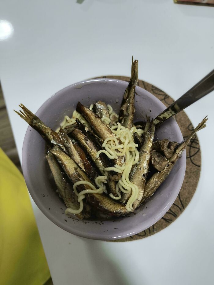 Bowl of unhinged food with ramen and sardines, ready to eat.