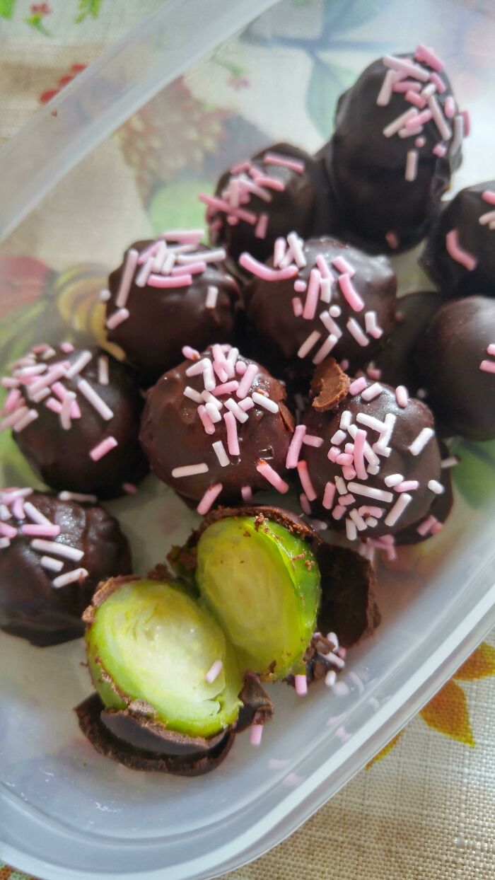 Unhinged food creation: Chocolate-covered Brussels sprouts with pink sprinkles in a plastic container.