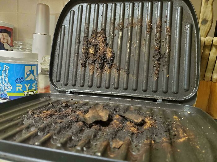 Dirty grill with burned food remnants, illustrating horrible roommates' cleaning habits.