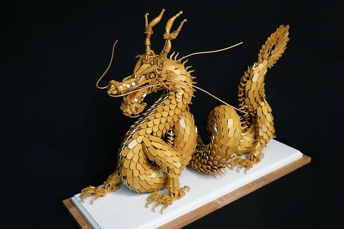 Majestic Lego build of a gold dragon sculpture on a white display stand.