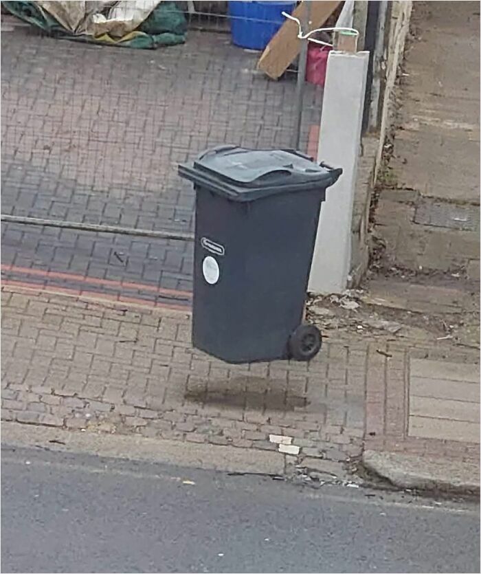 Floating trash bin illusion resembling bad renders on a city pavement.