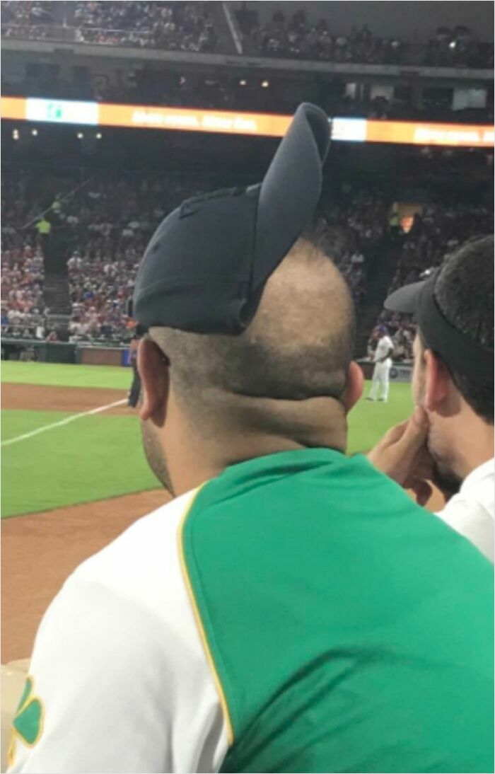 Man with a hat oddly positioned, resembling a render error, at a lively baseball game.