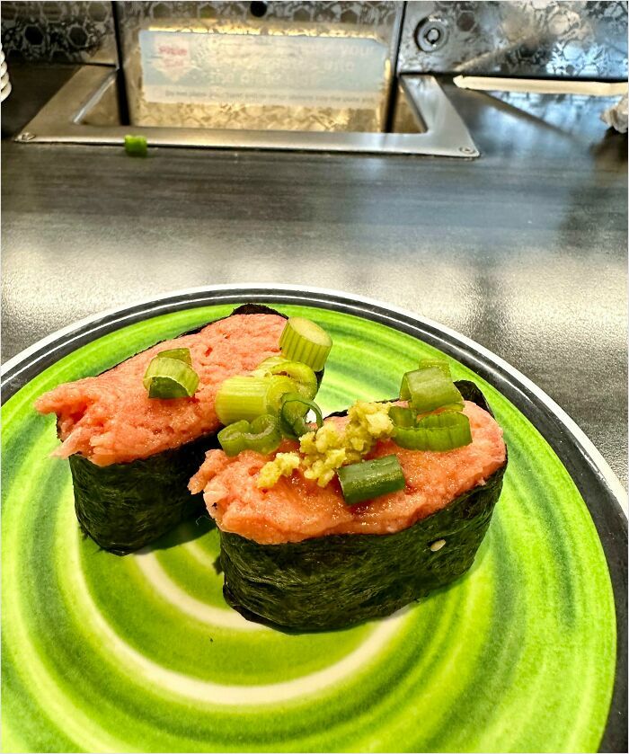 Sushi with green onions on a vibrant plate, resembling a digital render.