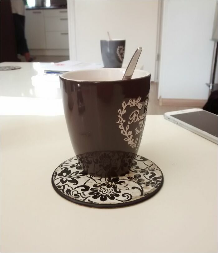 Coffee cup on a floral coaster in a kitchen, resembling a computer-generated render.