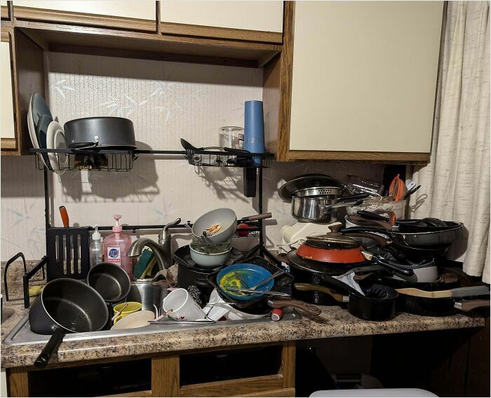 Cluttered kitchen sink overflowing with dirty dishes, illustrating the chaos of horrible roommates.