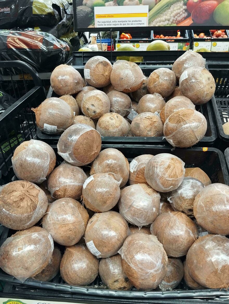 Coconuts with unnecessary plastic packaging in a supermarket display.