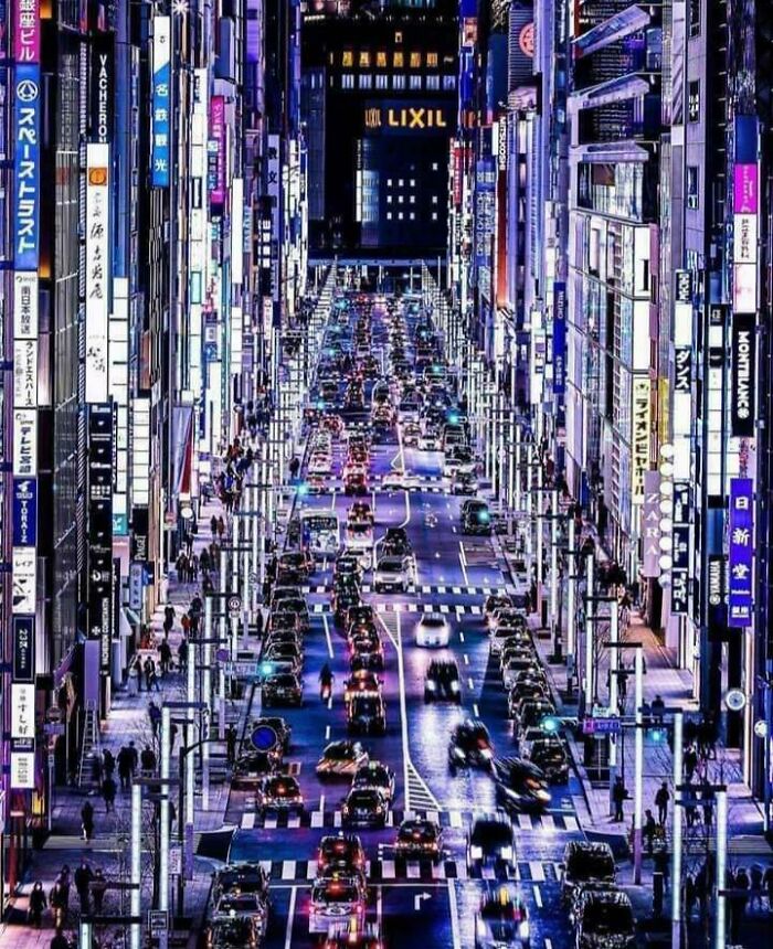 A vibrant city street at night, showcasing incredible world photos with bright neon lights and heavy traffic.