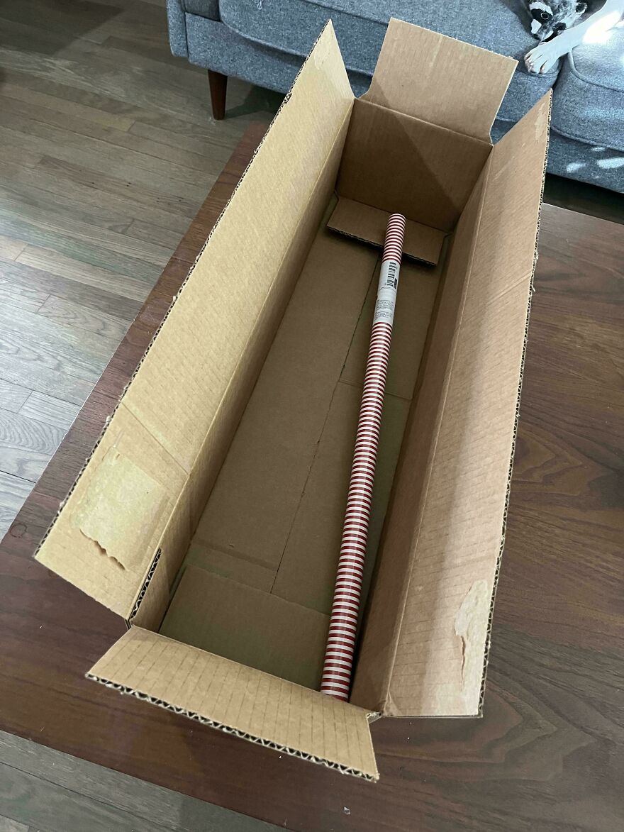 Long cardboard box with a single roll of wrapping paper highlights wasteful unnecessary packaging.