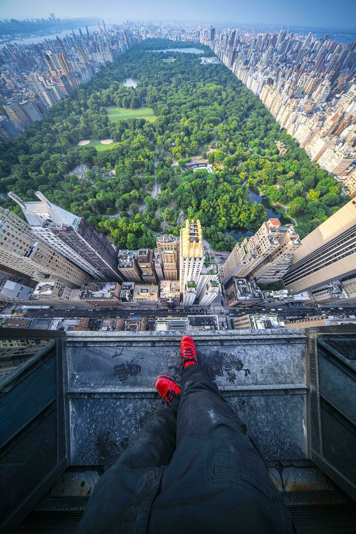 View of Central Park from a skyscraper edge, featuring red shoes and an incredible world perspective.