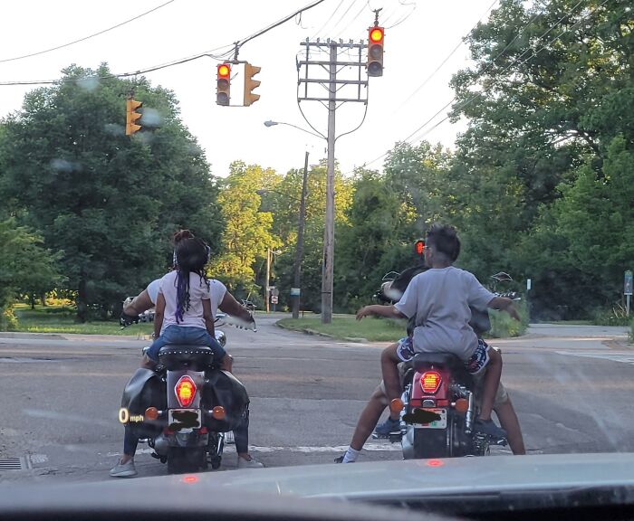 Children on motorcycles at a traffic light, showcasing ignorant behavior by parents.