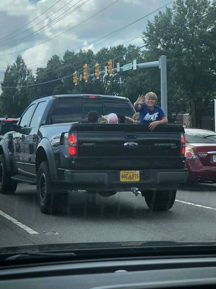 Children riding unsafely in the back of a truck, highlighting ignorant-parents unaware of safety risks.