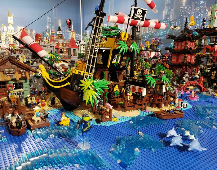 LEGO pirate ship and village scene with vibrant details in a large build, including ocean waves and palm trees.