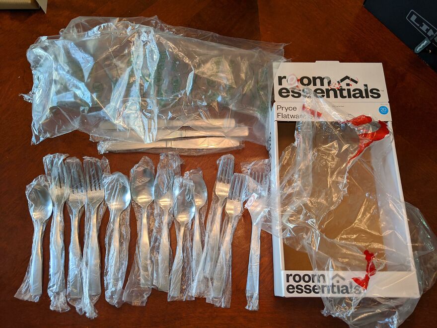 Excessive plastic packaging for cutlery set spread across a table, highlighting unnecessary waste.