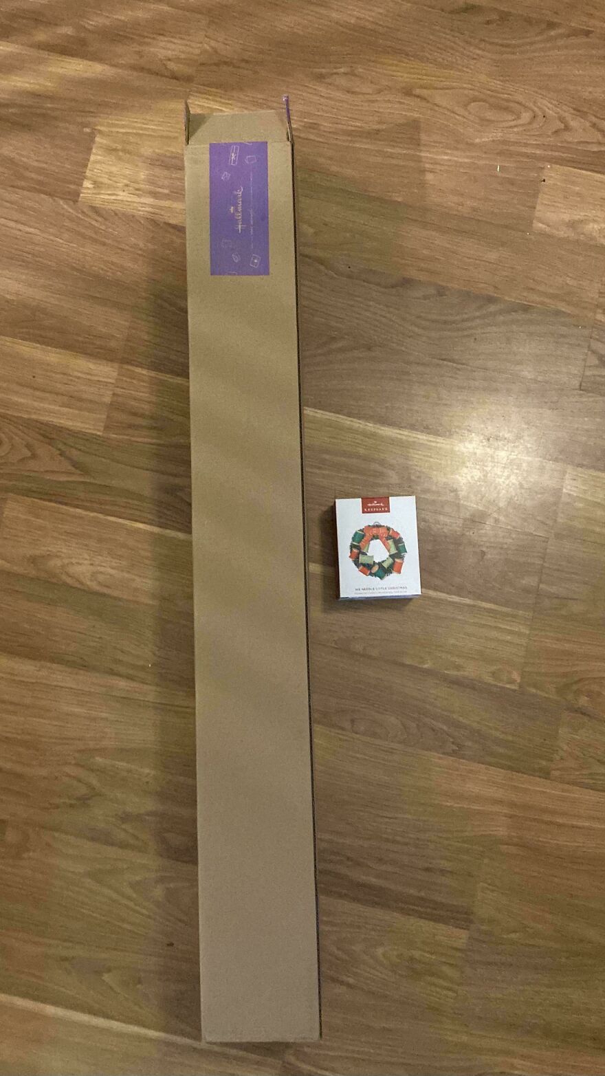 Long brown box on the floor next to a small wreath box, highlighting unnecessary packaging.