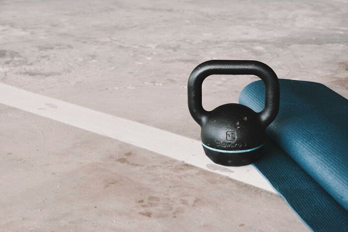 Kettlebell and yoga mat on concrete floor, illustrating frugal home fitness hacks.