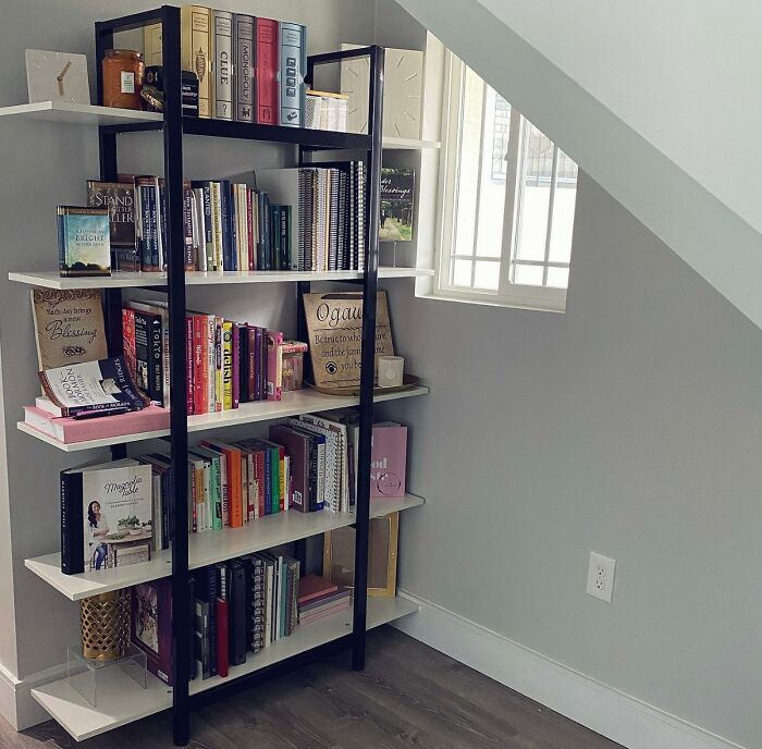 Bookshelf neatly organized with colorful books and decorative items under a sloped ceiling, optimizing small space.