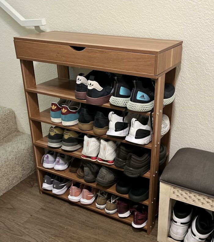 Wooden shoe rack filled with assorted sneakers, illustrating an organized storage solution.