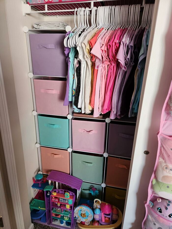 Neatly organized closet with colorful fabric bins and hanging clothes showcasing efficient organization.