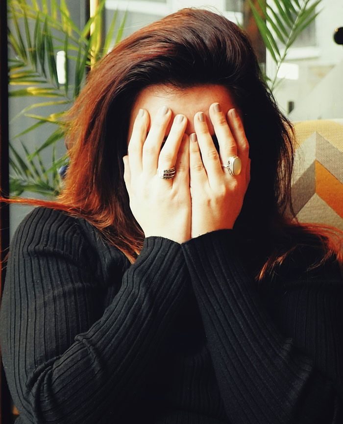 A woman covering her face with hands, expressing surprise or embarrassment in a speeding-related context.