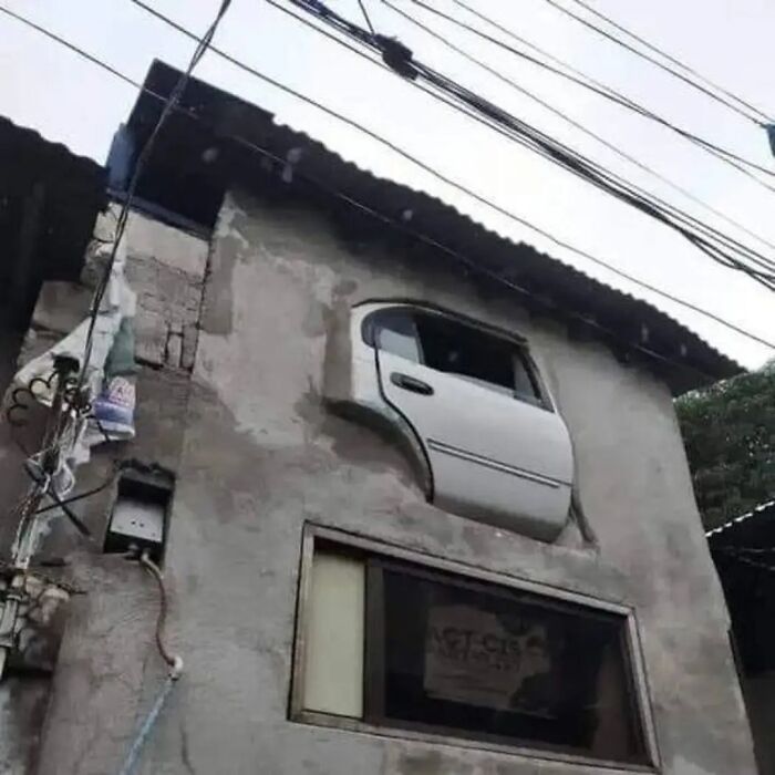 Car door installed as a window on a cement wall, illustrating funny construction fails.