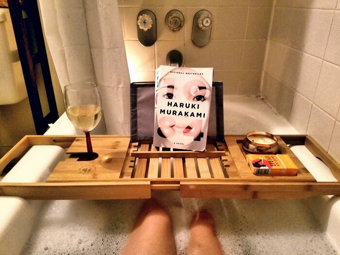 Bathtub setup with a book, wine, and candles—ideal gifts for antisocial people.