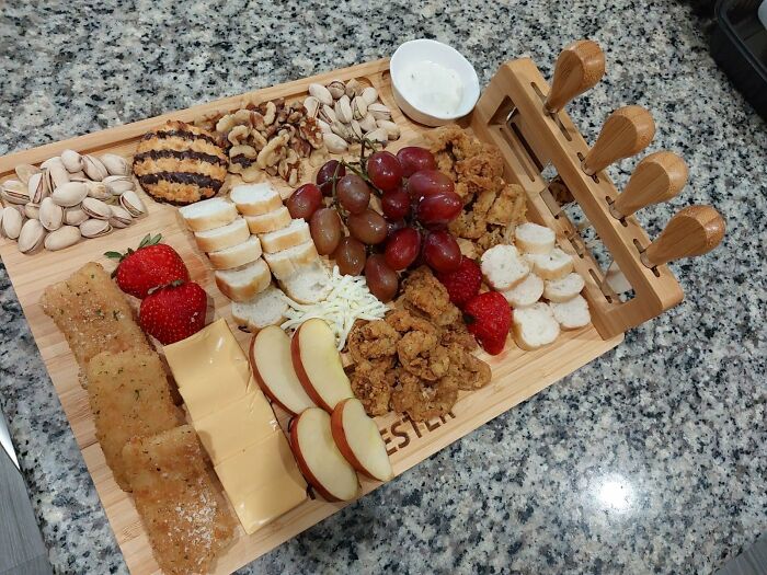 Charcuterie board with fruits, cheese, nuts, and bread on a granite countertop, perfect gifts for your mom.