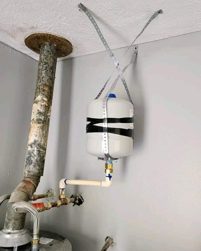 Amateur plumbing setup with water tank poorly secured to the ceiling, showcasing funny cheap construction fails.