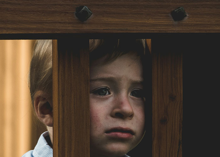 Child peering through wooden bars, evoking the emotions in memorable dispatcher calls.