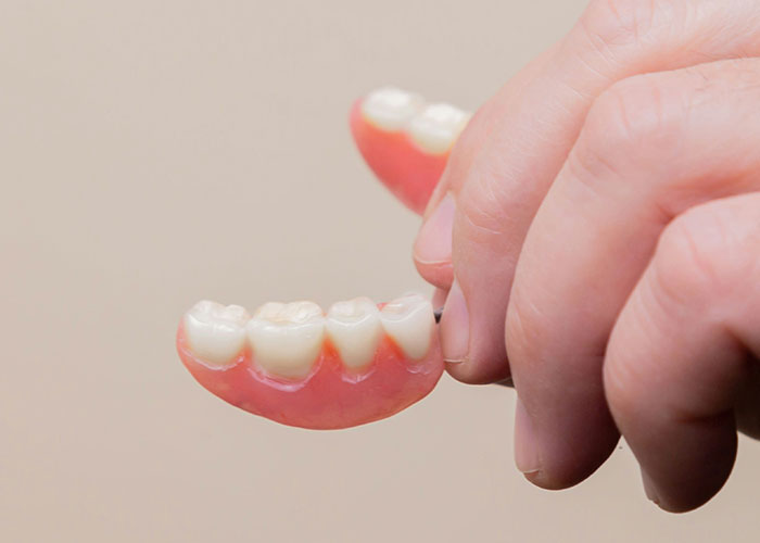 Holding a set of dentures, representing an unusual 911 call dispatcher memory.