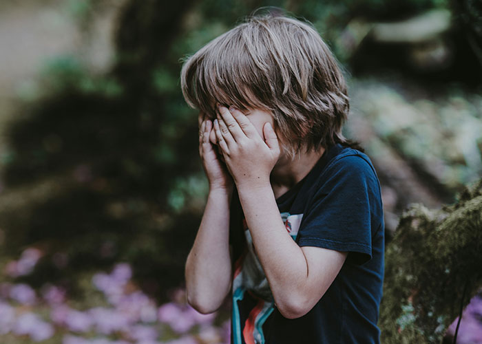 A child with blonde hair covering their face, outdoors, relating to memorable 911 calls.