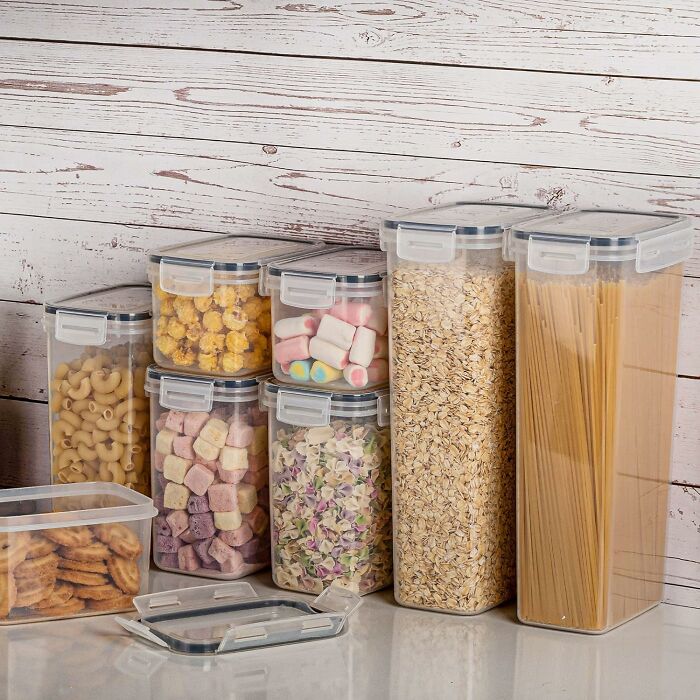 Clear containers filled with pasta, grains, and snacks on a wooden counter, highlighting new ways to organise your kitchen.