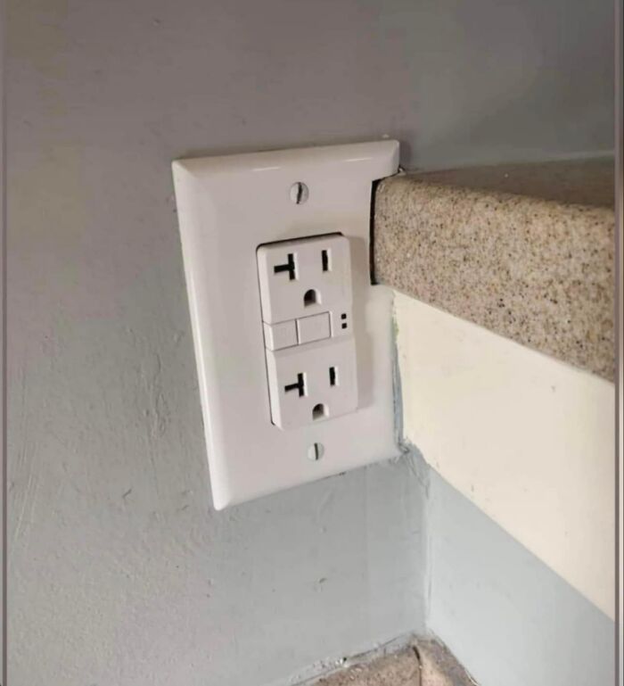 Funny cheap construction fail with a misaligned wall outlet blocked by a countertop.