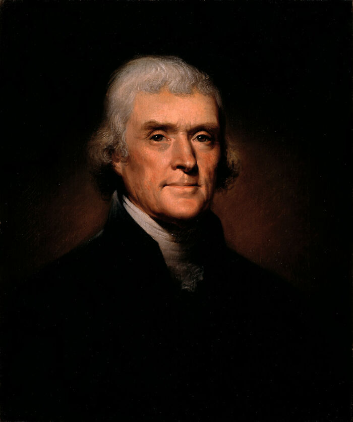 Portrait of a historical figure with significant influence on history, wearing a dark jacket against a dark background.