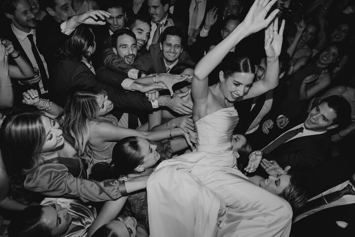 Bride joyously being lifted by guests, exemplifying one of the top wedding photos of 2024 in a lively celebration.