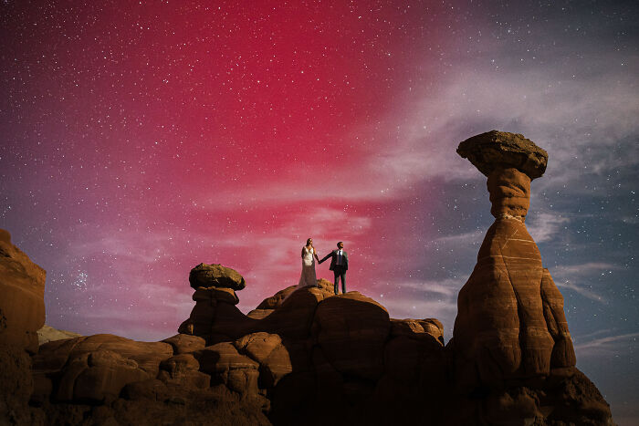 Bride and groom on a rock formation under a starry sky, highlighting a top wedding photo of 2024.