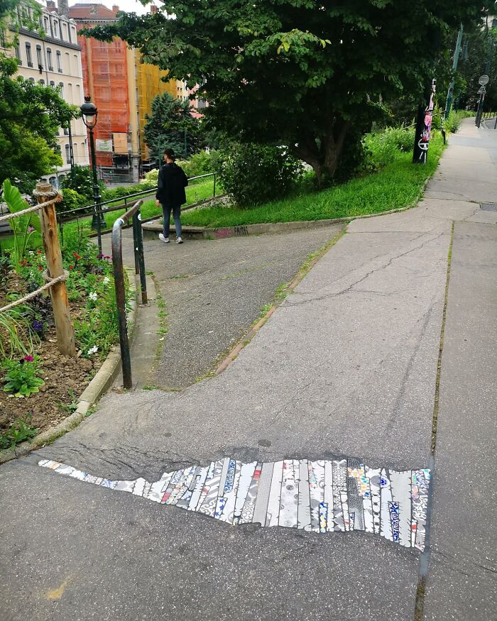 Vibrant mosaic artwork decorates a cracked sidewalk, adding color and creativity to the urban environment.