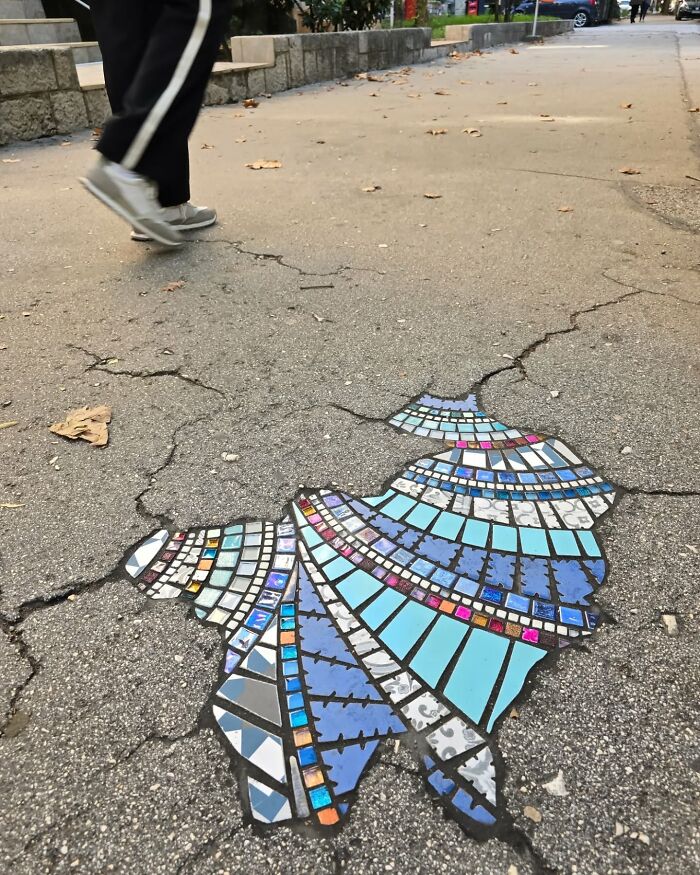 Vibrant mosaic art mends cracked sidewalk, adding color and creativity to the urban environment.