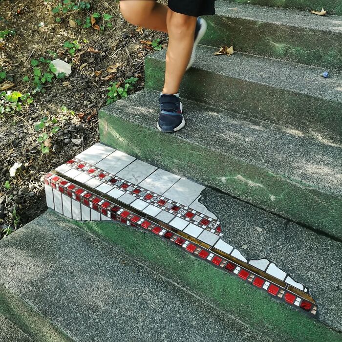 Person walking near vibrant mosaic art mending cracked steps.