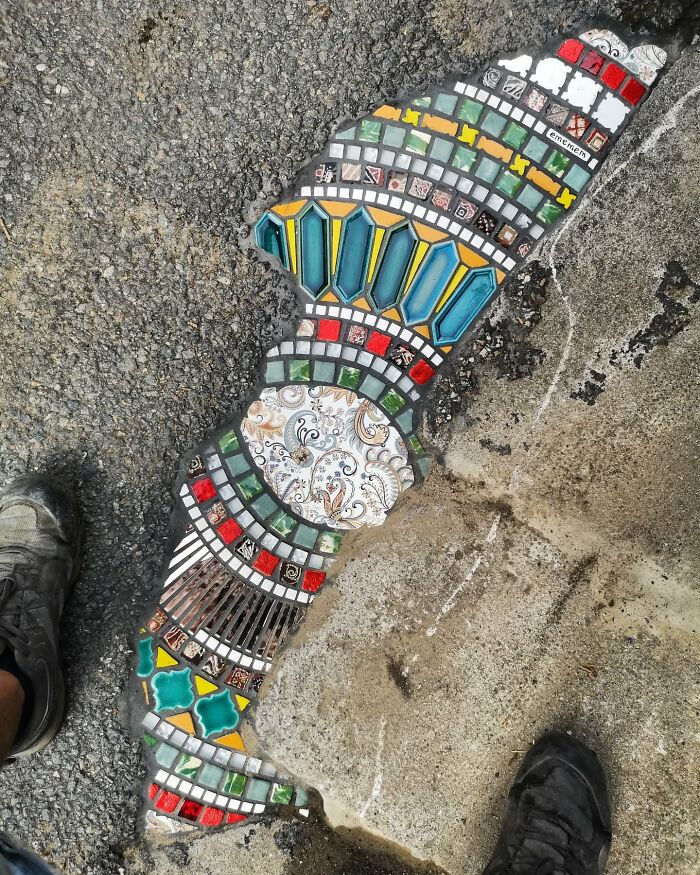 Vibrant mosaic art fills a cracked sidewalk, showcasing colorful tiles and intricate designs.