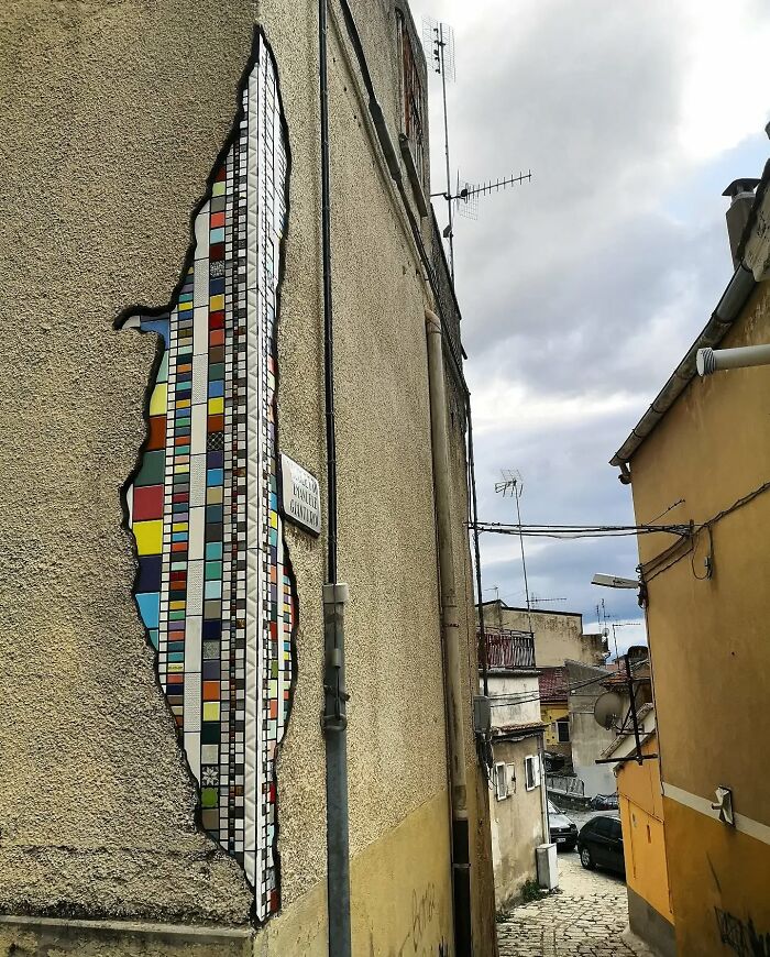 Vibrant mosaic art patching a cracked building wall, adding color and creativity to the urban landscape.