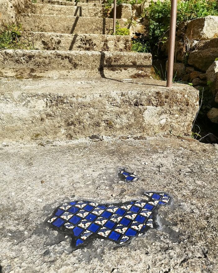 Vibrant mosaic art mends cracked sidewalk, blending blue tiles with stone surface.