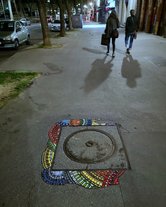 Vibrant mosaic art repairing a cracked sidewalk, adding color and creativity to urban infrastructure.