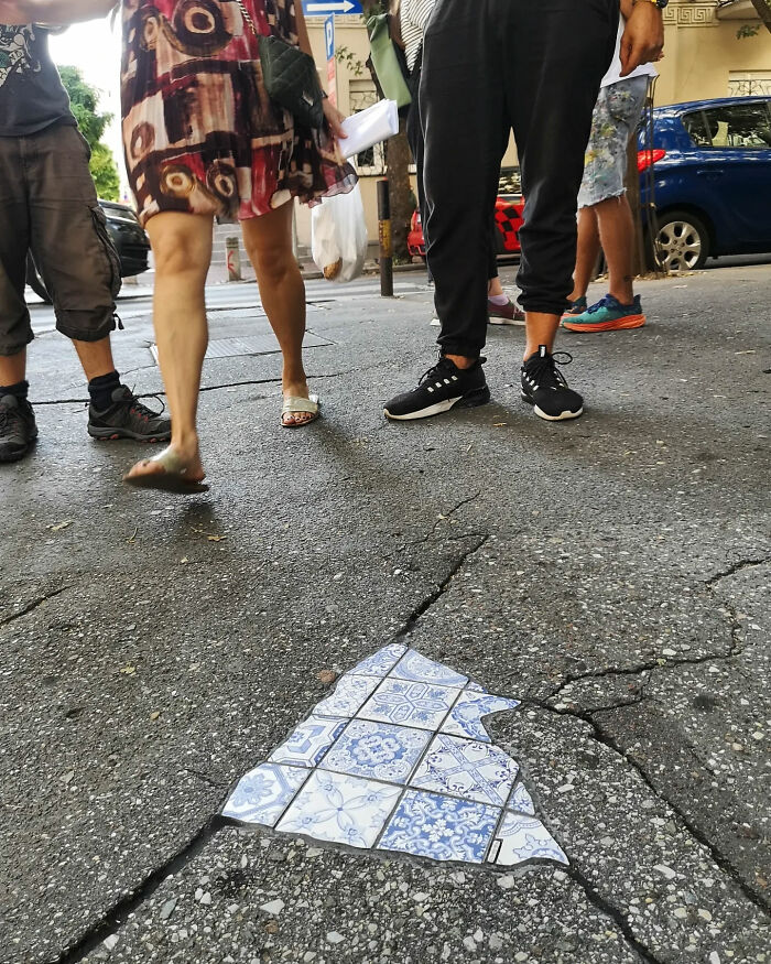 Vibrant mosaic art fills a cracked sidewalk, surrounded by pedestrians.