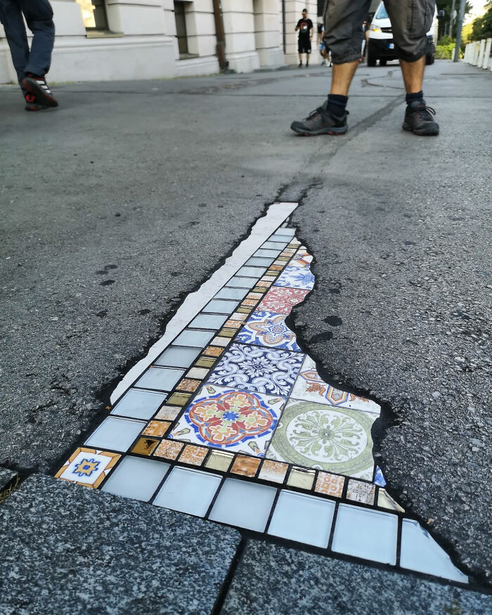 Vibrant mosaic art fills a cracked sidewalk, showcasing creative street repair.