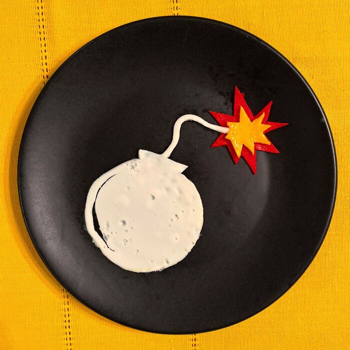 Creative egg art shaped like a bomb with a lit fuse on a black plate.