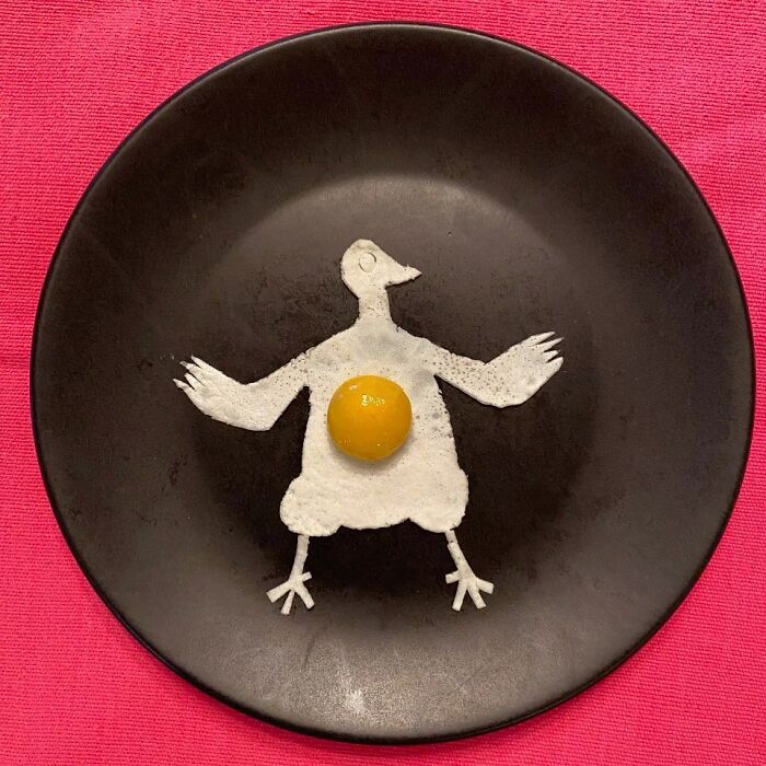 Creative egg art resembling a bird on a black plate.