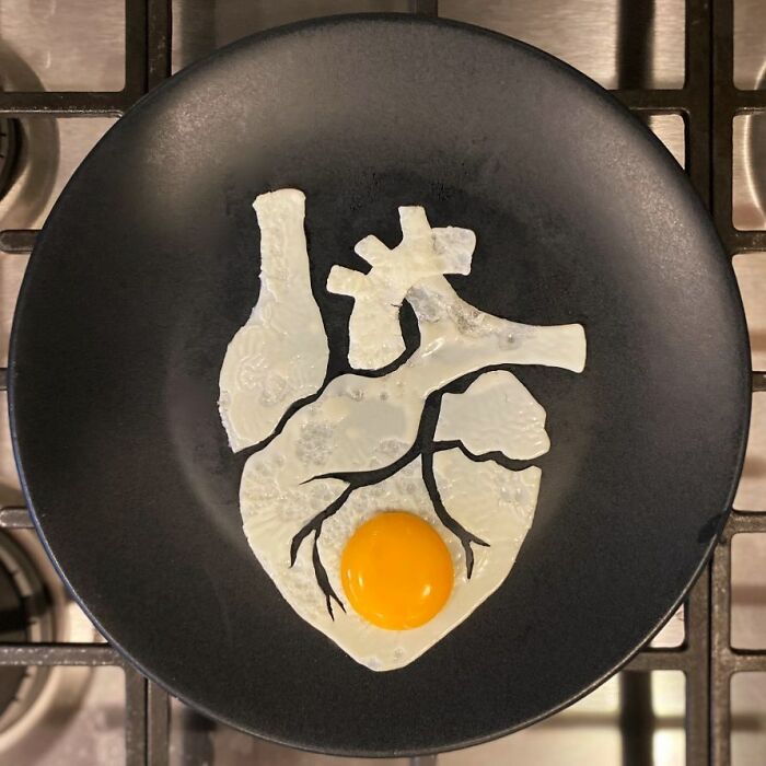 Creative egg art shaped like a heart on a black plate.